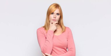 Kızıl saçlı güzel kadın ciddi görünüyor, kafası karışık, kararsız ve düşünceli, seçenekler ve seçenekler arasında şüpheci.