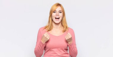 Kızıl saçlı güzel kadın zaferle bağırıyor, gülüyor, mutlu ve heyecanlı hissediyor başarıyı kutlarken.