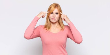 Ciddi ve konsantre bakışlı, beyin fırtınası yapan ve zorlu bir sorunu düşünen kızıl saçlı güzel bir kadın.