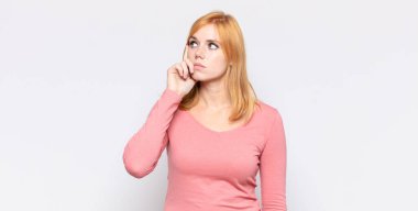 Kızıl saçlı, güzel bir kadın, yoğun bakışlı, şüpheli bir ifadeyle merak ediyor, yukarı ve yana bakıyor.