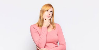 Kızıl saçlı güzel kadın, düşünüyor, kuşkulu ve şaşkın hissediyor, farklı seçeneklerle, hangi kararı vereceğini merak ediyor.