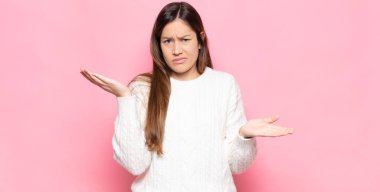 Şaşkın, kafası karışmış ve stresli görünen genç bir kadın. Farklı seçenekler arasında merak ediyor, kararsız.