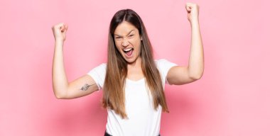 Genç ve güzel bir kadın muzaffer bir şekilde bağırıyor. Heyecanlı, mutlu ve şaşırmış görünüyor. Kutlama yapıyor.