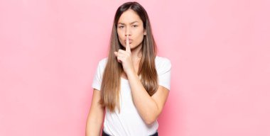 Genç ve güzel bir kadın sessizlik ve sessizlik istiyor, parmaklarıyla ağzının önünde işaret ediyor, 