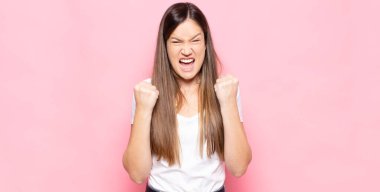 Genç ve güzel bir kadın zaferle bağırıyor, gülüyor, mutlu ve heyecanlı hissediyor başarıyı kutlarken.