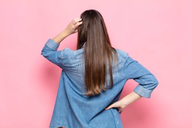 Genç, güzel bir kadın bilgisiz ve kafası karışık hissediyor, bir çözüm düşünüyor, eli kalçasında, diğeri kafasında, dikiz aynasından.