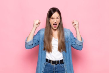 Genç, güzel bir kadın mutlu, pozitif ve başarılı hissediyor, zaferi, başarıları ya da iyi şansı kutluyor.