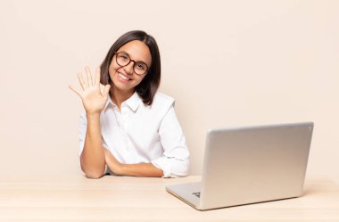 Gülümsüyor ve dost canlısı görünüyor, 5 ya da 5 numarayı gösteriyor, el önde, geriye doğru sayıyor.