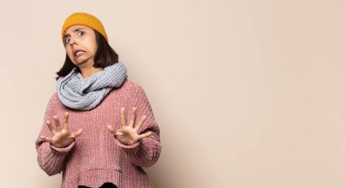 Genç kadın şok olmuş ve korkmuş hissediyor, ağzı açık ve elleri yanaklarında korkmuş görünüyor.