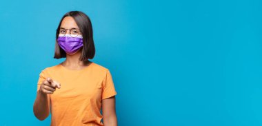 Genç bir kadın kameraya tatmin olmuş, kendinden emin, dostane bir gülümsemeyle bakıyor ve seni seçiyor.