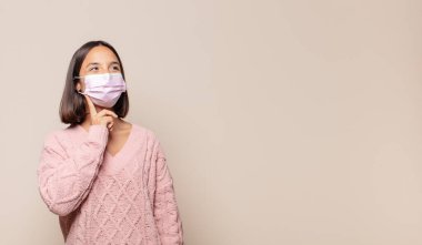 Genç kadın mutlu bir şekilde gülümsüyor ve hayal kuruyor ya da şüphe ediyor.