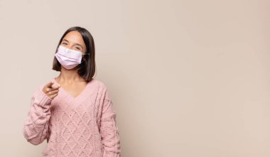 Genç bir kadın kameraya tatmin olmuş, kendinden emin, dostane bir gülümsemeyle bakıyor ve seni seçiyor.