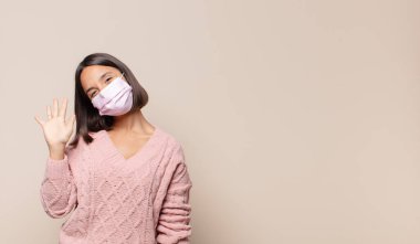 Genç bir kadın gülümsüyor ve arkadaş canlısı görünüyor, 5 ya da 5 numarayı gösteriyor, elleri önde, geriye doğru sayıyor.