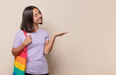 Neşeli bir şekilde gülümseyen genç bir kadın, mutlu hissediyor ve fotokopi alanında avucunun içinde bir konsept gösteriyor.