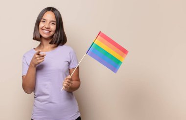 Genç bir kadın kameraya tatmin olmuş, kendinden emin, dostane bir gülümsemeyle bakıyor ve seni seçiyor.