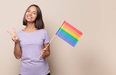 Genç kadın gülümsüyor ve mutlu görünüyor, kaygısız ve olumlu, zafer ya da barış simgesi.