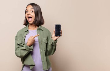 Genç bir kadın heyecanlı ve şaşırmış görünüyor. Yana ve yukarıya bakıp boşluğu kopyalıyor.