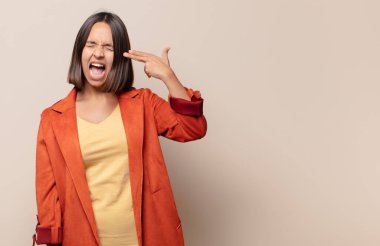 Genç bir kadın mutsuz ve stresli görünüyor, intihar jesti silahla işaret ediyor, kafasını işaret ediyor.