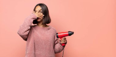 Şok olmuş, korkmuş ya da korkmuş görünüyor, yüzleri elle kaplıyor ve parmaklarının arasına bakıyor.