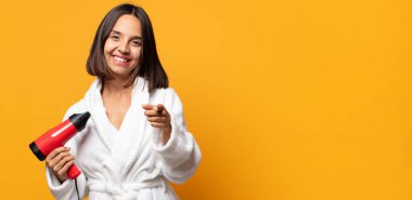 Tatmin olmuş, kendine güvenen, dost canlısı bir gülümsemeyle kameraya bakıp seni seçiyor.