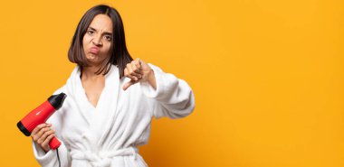 Kızgın, sinirli, hayal kırıklığına uğramış ya da hoşnutsuz, ciddi bir bakışla başparmaklarını aşağı gösteren.