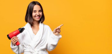 Neşeli bir şekilde gülümseyen, mutlu hisseden, kenarı ve yukarıyı gösteren, kopya uzayda nesneleri gösteren