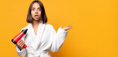 Şaşırmış ve şoke olmuş bir halde, çenesi düşmüş bir objeyi elinde açık bir elle tutarken.