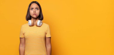 Şaşırmış ve kafası karışmış görünüyor, sinirsel bir hareketle dudağını ısırıyor, sorunun cevabını bilmiyor.