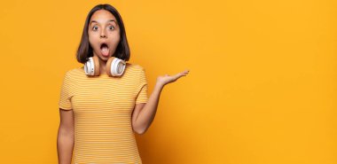 Şaşırmış ve şoke olmuş bir halde, çenesi düşmüş bir objeyi elinde açık bir elle tutarken.