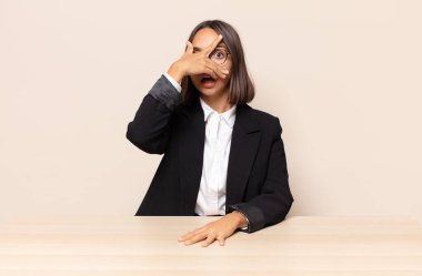 Şok olmuş, korkmuş ya da korkmuş görünüyor, yüzleri elle kaplıyor ve parmaklarının arasına bakıyor.