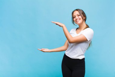 Genç İspanyol kadın gülümsüyor, mutlu, pozitif ve memnun, fotokopi alanında nesne ya da konsept tutuyor ya da gösteriyor