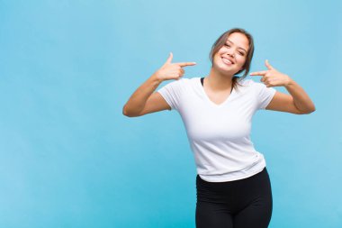 Genç İspanyol kadın kendine güvenerek gülümsüyor. Geniş gülümseme, pozitif, rahat, tatmin olmuş tavır.