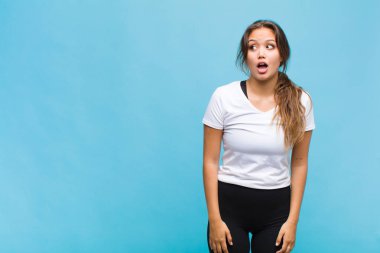 Genç İspanyol kadın şok olmuş, mutlu, şaşkın ve şaşırmış hissediyor, ağzı açık bir şekilde yana bakıyor.