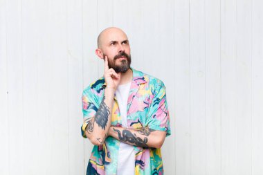 Kel adam mutlu bir şekilde gülümsüyor ve hayal kuruyor ya da şüphe ediyor.