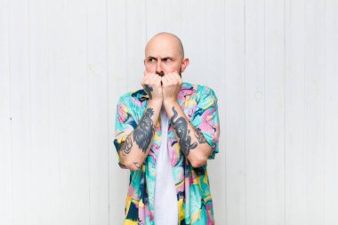 Kel adam endişeli, gergin, stresli ve korkmuş görünüyor. Tırnaklarını yiyor ve yanal fotokopi alanı arıyor.