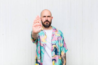 Kel adam ciddi, sert, hoşnutsuz ve kızgın görünüyor. Avuç içini açıp jesti durduruyor.