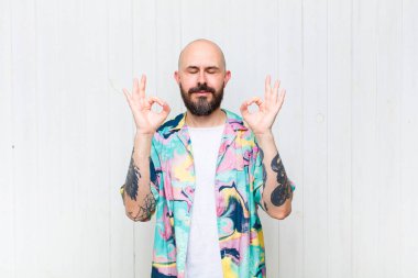 Kel adam odaklanmış ve meditasyon yapıyor, tatmin olmuş ve rahatlamış hissediyor, düşünüyor ya da bir seçim yapıyor.