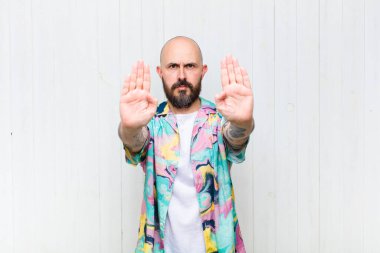 Kel adam ciddi görünüyor, mutsuz, kızgın ve hoşnutsuz giriş yasaklandı ya da her iki avuçta da dur diyor.