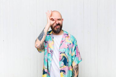 Kel adam mutlu bir şekilde gülümsüyor, şaka yapıyor ve gözetleme deliğinden bakıyor, sırları gözetliyor.