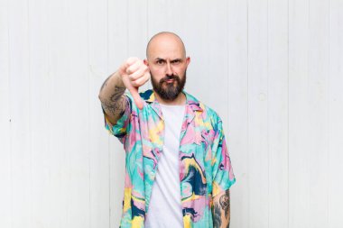 Kel bir adam kızgın, sinirli, hayal kırıklığına uğramış ya da canı sıkkın, ciddi bir bakışla başparmağını kaldırıyor.