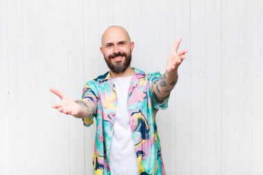 Kel adam neşeyle gülümsüyor sıcak, dostça, sevgi dolu bir kucak veriyor, mutlu ve sevimli hissediyor.