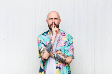 Kel adam ciddi görünüyor ve parmaklarını dudaklarına bastırıp sessizlik ya da sessizlik talep ediyor, sır saklıyor.