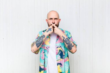 Kel adam ciddi görünüyor ve iki parmağının önde olması hoşnutsuzluk yaratıyor. Reddedilmek üzere, sessizlik istiyor.