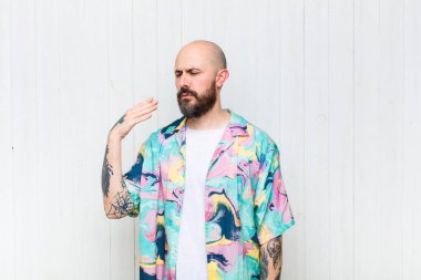 Kel bir adam stresli, endişeli, yorgun ve hayal kırıklığına uğramış, gömleğini çekmiş, sorunlu görünüyor.