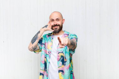 Kel adam neşeyle gülümsüyor ve kamerayı işaret ediyor. Sonra seni arıyor, telefonla konuşuyor.