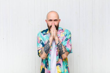 Kel bir adam endişeli, umutlu ve dindar, avuçlarına bastırılmış ve af dilenen sadık bir şekilde dua ediyor.