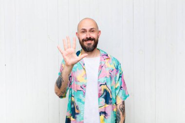 Kel adam gülümsüyor ve dost canlısı görünüyor. 5 ya da 5 numarayı gösteriyor. Eli önde, geriye doğru sayıyor.