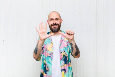 Kel adam gülümsüyor ve arkadaş canlısı görünüyor, altı ya da altıncı numarayı gösteriyor, eli önde, geriye doğru sayıyor.