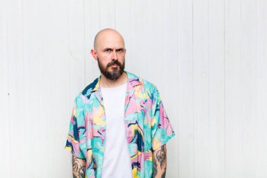 Kel bir adam üzgün, üzgün ya da kızgın. Olumsuz bir tavır sergiliyor, anlaşmazlık içinde kaşlarını çatıyor.