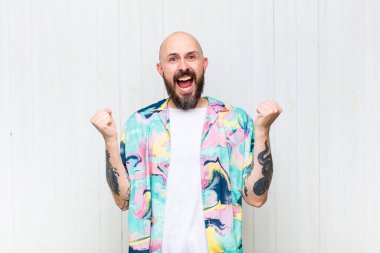 Kel adam son derece mutlu ve şaşırmış görünüyor, başarıyı kutluyor, bağırıyor ve zıplıyor.